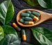 wooden-spoon-holding-green-orange-supplement-pills-resting-wooden-table-background_166222-19636